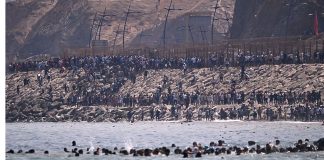 People are gathered near the border fence in Ceuta following a mass influx from Morocco