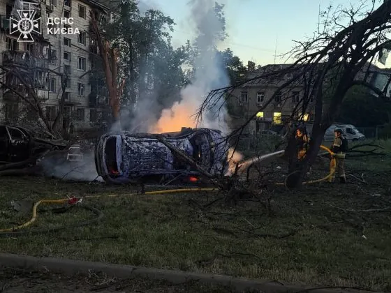 Палаючий автомобіль біля житлових будинків після російського ракетного удару по Києву.