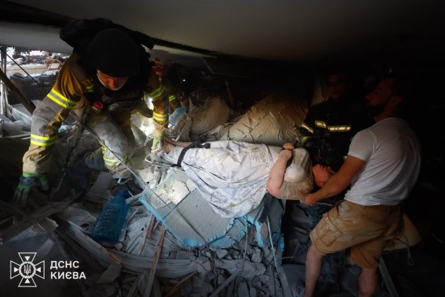 Rescue workers from the State Emergency Service are evacuating an injured woman from under the rubble following a Russian attack on Kyiv.
