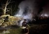У Києві після нічної атаки горіли склади, автівки та пошкоджено школу-інтернат Рятувальник ДСНС ліквідовує пожежу серед знищених автомобілів після ракетної атаки на Київ у ніч на 14 липня 2026 року.