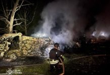 A State Emergency Service firefighter is putting out a fire amongst wrecked cars following a missile attack on Kyiv on the night of 14 July 2026.