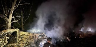 У Києві після нічної атаки горіли склади, автівки та пошкоджено школу-інтернат Рятувальник ДСНС ліквідовує пожежу серед знищених автомобілів після ракетної атаки на Київ у ніч на 14 липня 2026 року.