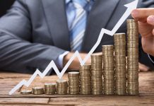Investing for Beginners: How to Protect Your Savings from Inflation and Generate Passive Income Stacks of coins rising up, and a graph with an upward-pointing arrow, set against the backdrop of a man in a suit.