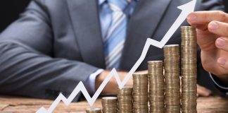 Investing for Beginners: How to Protect Your Savings from Inflation and Generate Passive Income Stacks of coins rising up, and a graph with an upward-pointing arrow, set against the backdrop of a man in a suit.