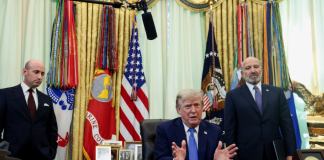 US President Donald Trump signs documents in the Oval Office