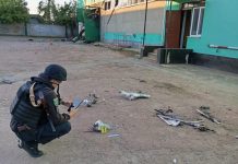 оліцейська фотографує уламки російського БпЛА біля пошкодженого будинку на Сумщині