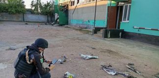 A policewoman is taking photographs of the wreckage of a Russian UAV near a damaged house in the Sumy region