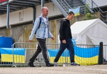 Ukrainian men standing outside the support centre holding Ukrainian flags