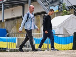 Чехія обмежила тимчасовий захист для чоловіків з України Українські чоловіки біля центру допомоги з прапорами України