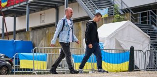 Українські чоловіки біля центру допомоги з прапорами України