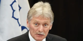 Чоловік у костюмі виступає перед мікрофоном під час офіційного заходу