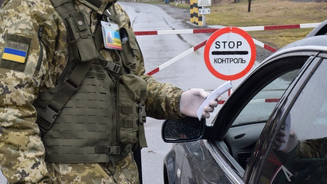Виїзд іноземців з України Український прикордонник перевіряє документи водія на пункті пропуску
