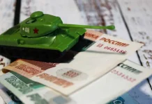 The Russian Federation’s budget deficit has reached 6.46 trillion roubles over seven months Russian roubles and a toy tank against the backdrop of the Russian Federation’s budget deficit