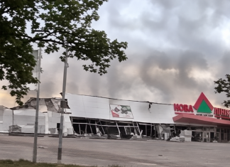 The damaged façade of the «Nova Linia» hypermarket and thick smoke rising above the building.
