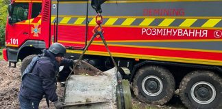 A State Emergency Service bomb disposal expert stands near the remains of an «Iskander-M» missile, which are being lifted by a crane in Kyiv.