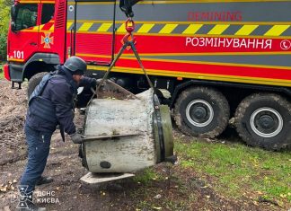A State Emergency Service bomb disposal expert stands near the remains of an «Iskander-M» missile, which are being lifted by a crane in Kyiv.