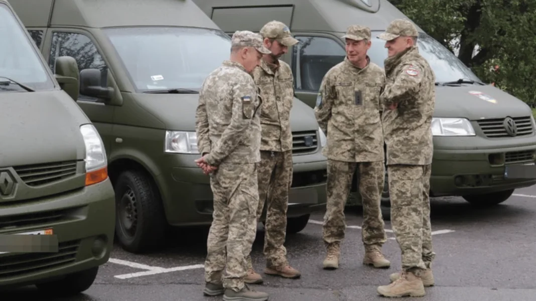 Четверо військових у камуфляжі розмовляють біля зелених службових мікроавтобусів Четверо військових у камуфляжі розмовляють біля зелених службових мікроавтобусів