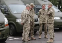Правила ТЦК і поліції: хто перевіряє документи та може затримати Четверо військових у камуфляжі розмовляють біля зелених службових мікроавтобусів