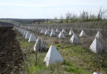 Ряди бетонних протитанкових загороджень типу «зуби дракона» та дротяні перешкоди вздовж дороги