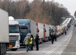 Довга черга вантажівок на автомобільній дорозі біля українсько-польського кордону