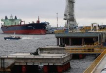 A large oil tanker with a dark hull near the port terminal for the transhipment of petroleum products