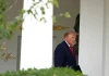 Президент США Дональд Трамп у темно-синьому костюмі та червоній краватці біля входу до Білого дому.