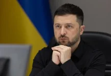 Ukrainian President Volodymyr Zelenskyy, wearing a black shirt, during a working meeting against the backdrop of the Ukrainian flag