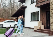 Як облаштувати паркування біля будинку, щоб газон не перетворювався на багнюку Приватний будинок із облаштованим подвір'ям і паркувальним місцем, біля якого стоїть білий автомобіль.