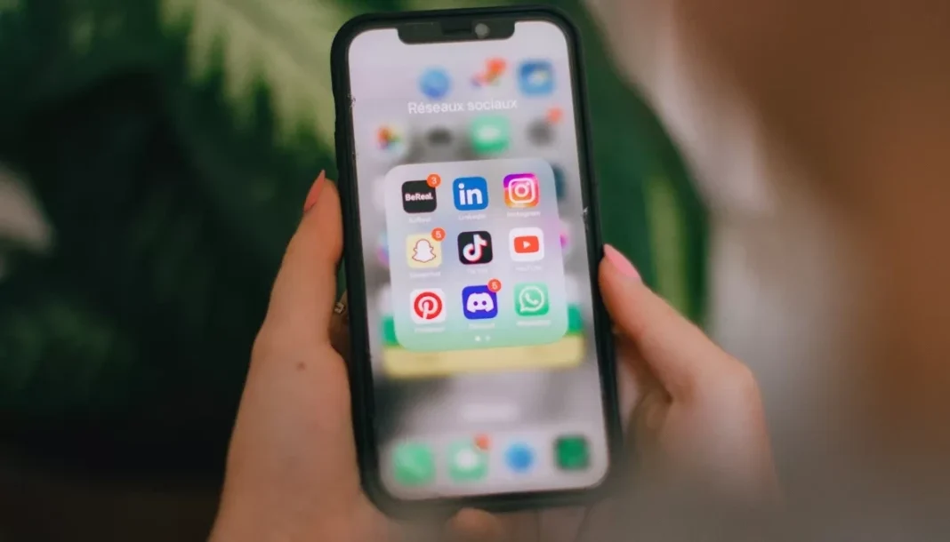 A smartphone with social media apps A smartphone in someone’s hands with the social media apps folder open