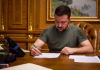 Зеленський підписав закони про ПДВ на онлайн-посилки та доходи платформ Володимир Зеленський підписує документ за робочим столом