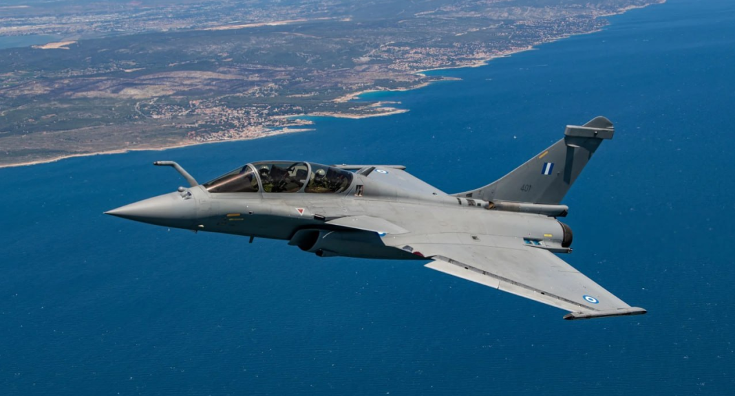 A two-seater Dassault Rafale fighter jet is flying over the sea along the coast