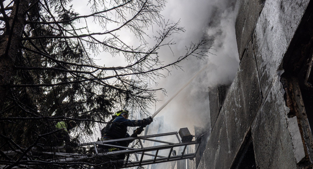 Rescue workers from the State Emergency Service are putting out a fire in a damaged building using a fire hose from a ladder truck.