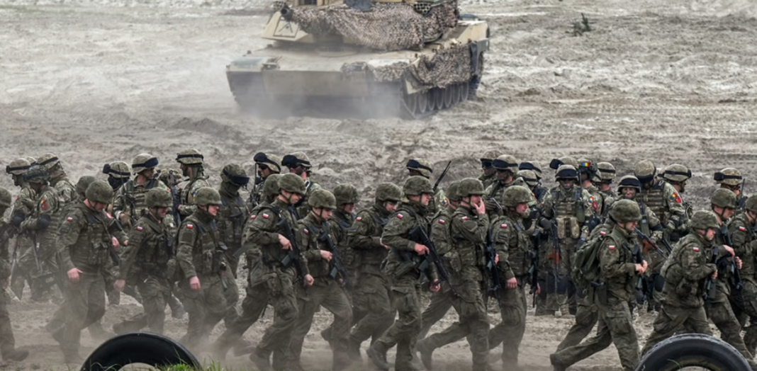 Military exercises Polish soldiers at a training ground, with armoured vehicles in the background