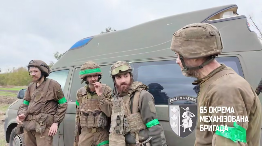Four soldiers in full kit are standing next to an evacuation minibus Four soldiers in full kit are standing next to an evacuation minibus