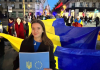 Українські та французькі активісти під час вечірньої ходи в Парижі несуть великі прапори України та плакат із символікою України і Євросоюзу.