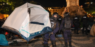 Police have dismantled 171 protesters’ tents in Portugal Police officers in protective gear are carrying a white camping tent across the square at night.