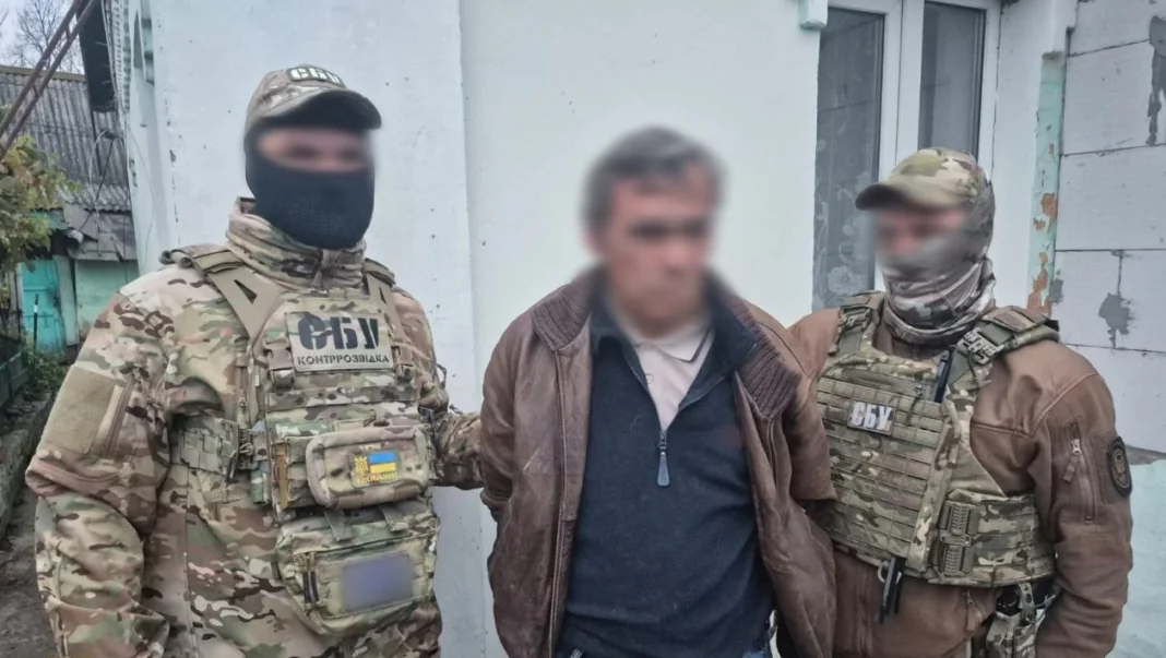 Затримання агента РФ Співробітники контррозвідки СБУ в тактичному спорядженні стоять поруч із затриманим чоловіком