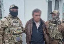 СБУ затримала агента ФСБ, який готував удари по київських ТЕЦ Співробітники контррозвідки СБУ в тактичному спорядженні стоять поруч із затриманим чоловіком