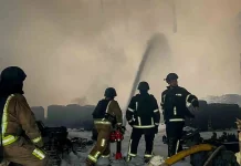 Рятувальники в захисному спорядженні гасять пожежу серед уламків у задимленому приміщенні