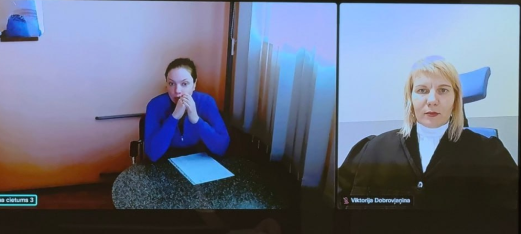 Polina Kamlova is taking part in a court hearing in Latvia via video link; Judge Anita Dzerve is visible next to her on the screen.