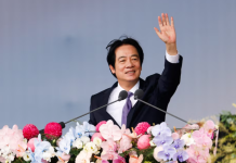 Lai Qingde is standing behind the podium with flowers