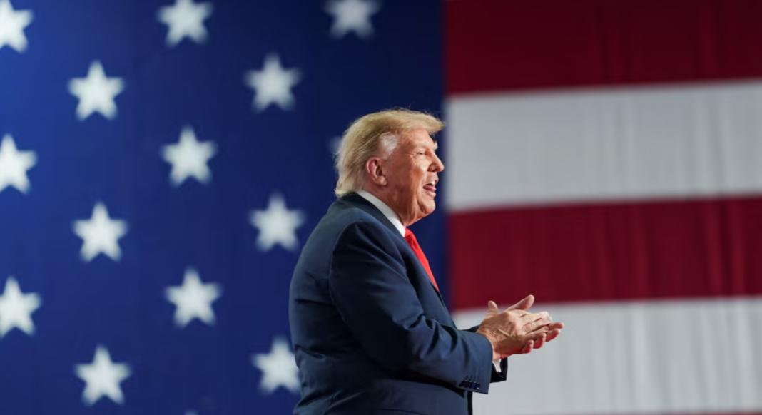 Donald Trump speaks against the backdrop of the US flag