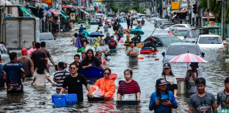 Bangkok on the brink: floods have turned the streets into lakes, with around 40 people killed People are walking along a flooded street in Bangkok