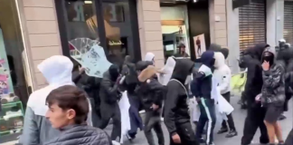 In Milan, 271 people were taken into police custody following the riots A group of hooded people outside a shop with a smashed window in Milan