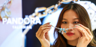Pandora has opened its largest factory in Vietnam at a cost of $150 million A woman is holding a silver Pandora bracelet with charms in front of her