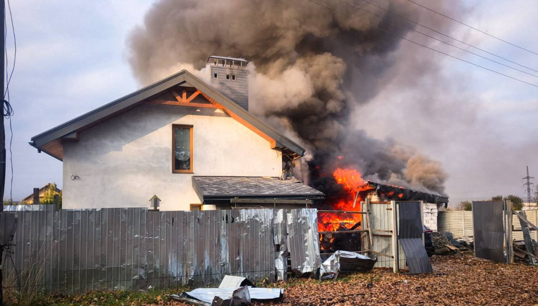 A major fire near a residential block: the flames have engulfed the outbuildings, and thick smoke is rising into the sky.
