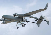 An aeroplane-type unmanned aerial vehicle with propellers and a landing gear, in flight against the backdrop of the sky.
