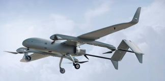 An aeroplane-type unmanned aerial vehicle with propellers and a landing gear, in flight against the backdrop of the sky.