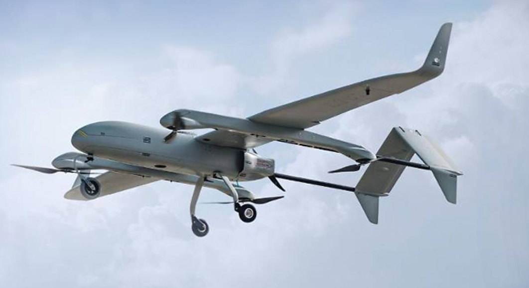 Drones in medicine An aeroplane-type unmanned aerial vehicle with propellers and a landing gear, in flight against the backdrop of the sky.
