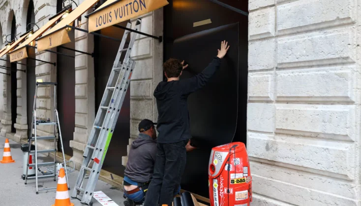 Працівники встановлюють захисні панелі на вітрини бутика Louis Vuitton у Франції